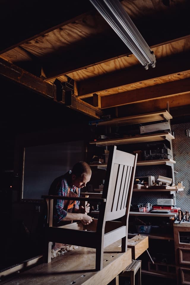 A woodworker at work on a chair in a small studio